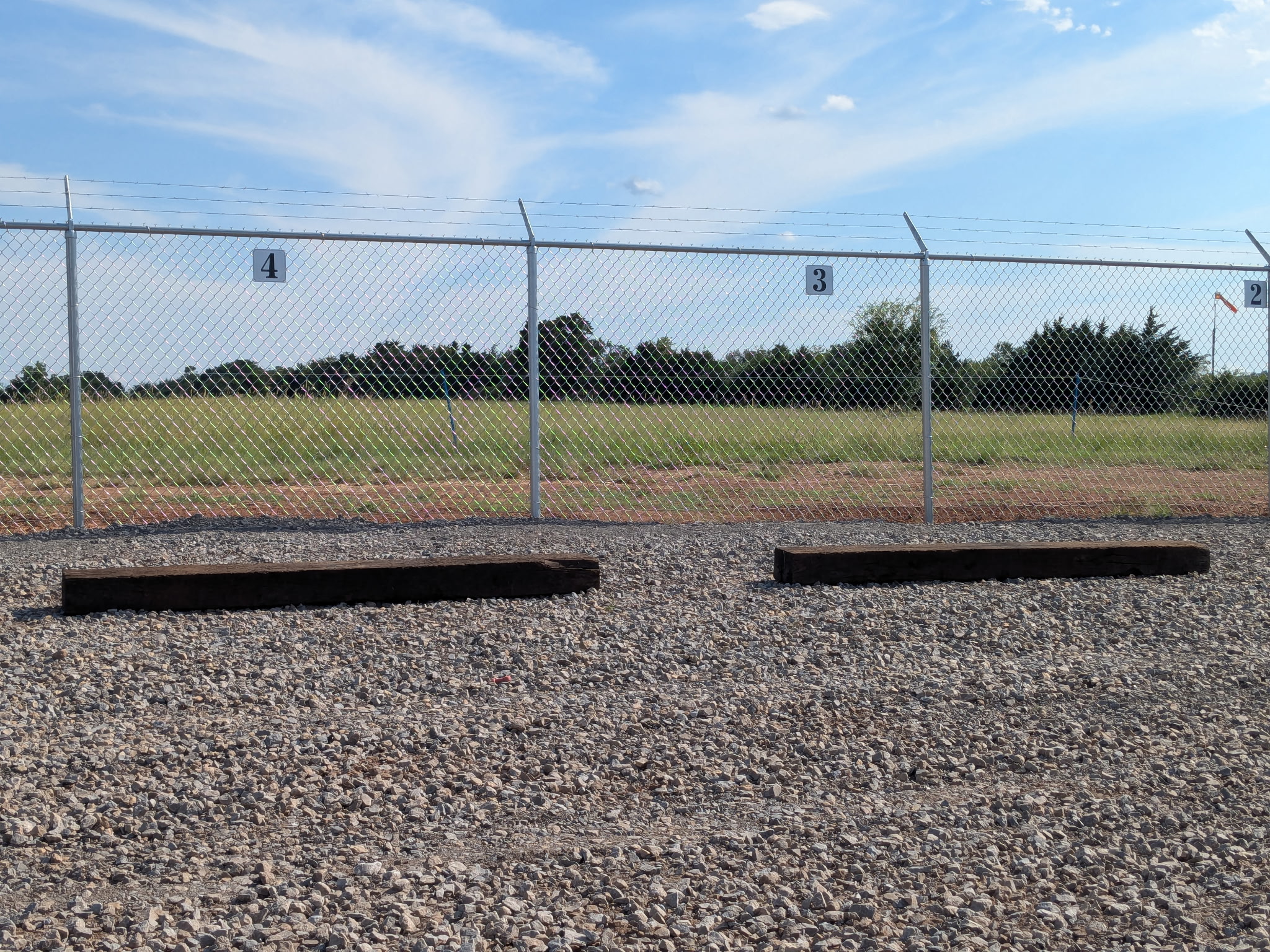 Numbered uncovered parking spaces along a security fence